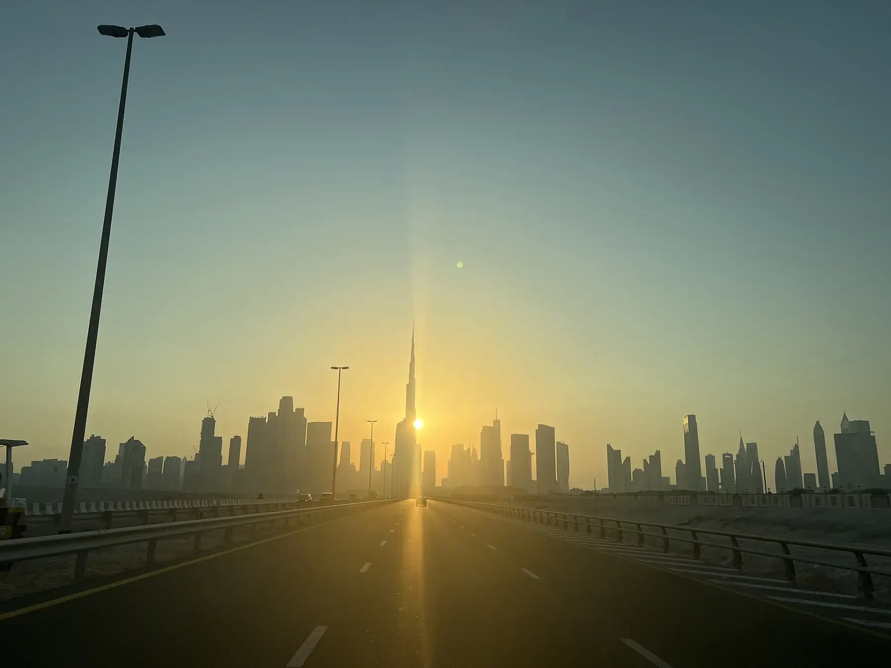 The Burj Khalifa against the setting sun, seen down the highway into Dubai.